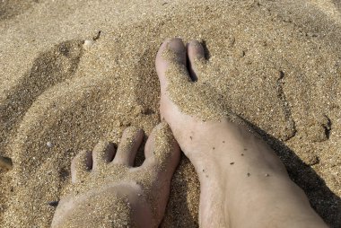 Kumsalda kadın ayaklarını kaplayan kum.