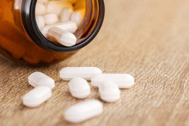 Ahşap arka planda şişe ve dağınık haplar