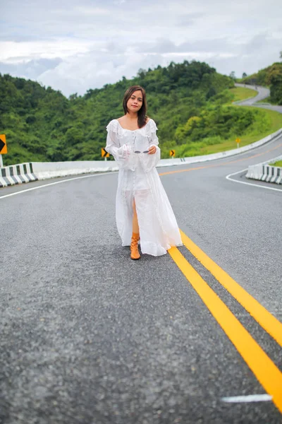 Beyaz elbiseli Asyalı turist kadın 3 numaralı yolda ya da dağların tepesinde Pua Bölgesi 'nden Bo Kluea Bölgesi' ne kadar yeşil ormanlı yolda..