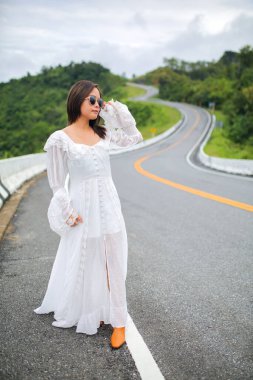 Beyaz elbiseli Asyalı turist kadın 3 numaralı yolda ya da dağların tepesinde Pua Bölgesi 'nden Bo Kluea Bölgesi' ne kadar yeşil ormanlı yolda..