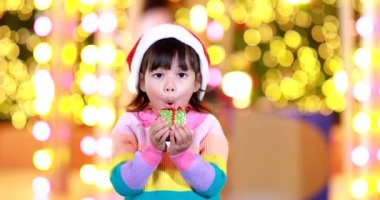 Yeni yıl beklentisi. Kırmızı bir Noel şapkası ve güzel bir renk tişörtü giyen ve arka planda Bokeh ışıkları olan tatlı küçük kız. Bu önemli sezonda iyi eğlenceler ve iyi eğlenceler..