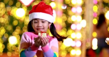 Yeni yıl beklentisi. Kırmızı bir Noel şapkası ve güzel bir renk tişörtü giyen ve arka planda Bokeh ışıkları olan tatlı küçük kız. Bu önemli sezonda iyi eğlenceler ve iyi eğlenceler..
