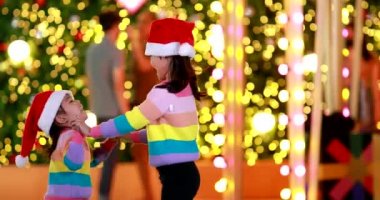 Yeni yıl beklentisi. Kırmızı bir Noel şapkası ve güzel bir renk tişörtü giyen iki tatlı kız. Arka planda Bokeh ışıkları var..