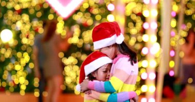 Yeni yıl beklentisi. Kırmızı bir Noel şapkası ve güzel bir renk tişörtü giyen iki tatlı kız. Arka planda Bokeh ışıkları var..