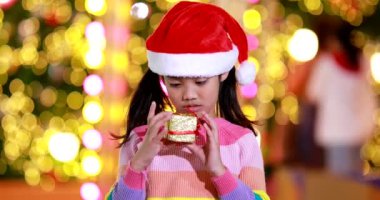 Yeni yıl beklentisi. Kırmızı bir Noel şapkası ve güzel bir renk tişörtü giyen ve arka planda Bokeh ışıkları olan tatlı küçük kız. Bu önemli sezonda iyi eğlenceler ve iyi eğlenceler..