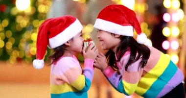Yeni yıl beklentisi. Kırmızı bir Noel şapkası ve güzel bir renk tişörtü giyen iki tatlı kız. Arka planda Bokeh ışıkları var..