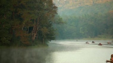 Pang Ung, Mae Hong Son, Tayland - 19 Aralık 2021: Sabahları ağaçlar ve doğa manzarasıyla gölün üzerinde yüzen bambu rafting yapan turist.