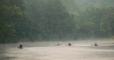 Pang Ung, Mae Hong Son, Tayland - 19 Aralık 2021: Sabahları ağaçlar ve doğa manzarasıyla gölün üzerinde yüzen bambu rafting yapan turist.
