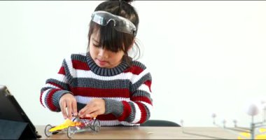 Fen dersinde evde robot araba yapan Asyalı küçük kız. Bu da gelişimini arttırıyor ve öğrenme becerilerini geliştiriyor. Teknolojiyle çalışan yetenekli zeki çocuklar..