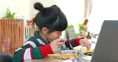 Fen dersinde evde robot araba yapan Asyalı küçük kız. Bu da gelişimini arttırıyor ve öğrenme becerilerini geliştiriyor. Teknolojiyle çalışan yetenekli zeki çocuklar..