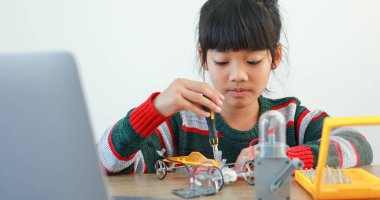 Fen dersinde evde robot araba yapan Asyalı küçük kız. Bu da gelişimini arttırıyor ve öğrenme becerilerini geliştiriyor. Teknolojiyle çalışan yetenekli zeki çocuklar..