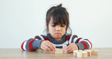Küçük kız tahta yapı blokları Jenga ile oynuyor. Eğlenmek ve yaratıcılığı öğrenmek. Öğrenme ve yeteneklerini geliştirme. Akıllı çocuk konsepti..