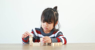 Küçük kız tahta yapı blokları Jenga ile oynuyor. Eğlenmek ve yaratıcılığı öğrenmek. Öğrenme ve yeteneklerini geliştirme. Akıllı çocuk konsepti..