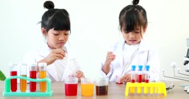 Küçük tatlı Asyalı öğrenci araştırma yapmayı ve kimyasal deney yapmayı öğrenirken evdeki test tüpünde sıvıyı analiz edip karıştırıyor..