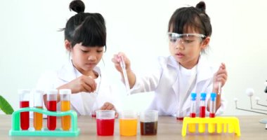 Küçük tatlı Asyalı öğrenci araştırma yapmayı ve kimyasal deney yapmayı öğrenirken evdeki test tüpünde sıvıyı analiz edip karıştırıyor..