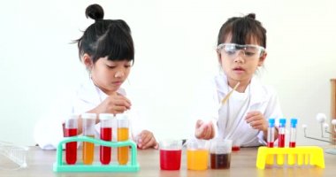 Küçük tatlı Asyalı öğrenci araştırma yapmayı ve kimyasal deney yapmayı öğrenirken evdeki test tüpünde sıvıyı analiz edip karıştırıyor..