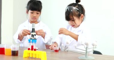 Küçük tatlı Asyalı öğrenci araştırma yapmayı ve kimyasal deney yapmayı öğrenirken evdeki test tüpünde sıvıyı analiz edip karıştırıyor..