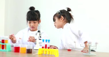 Küçük tatlı Asyalı öğrenci araştırma yapmayı ve kimyasal deney yapmayı öğrenirken evdeki test tüpünde sıvıyı analiz edip karıştırıyor..