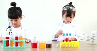 Küçük tatlı Asyalı öğrenci araştırma yapmayı ve kimyasal deney yapmayı öğrenirken evdeki test tüpünde sıvıyı analiz edip karıştırıyor..