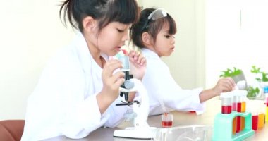 Küçük tatlı Asyalı öğrenci araştırma yapmayı ve kimyasal deney yapmayı öğrenirken evdeki test tüpünde sıvıyı analiz edip karıştırıyor..