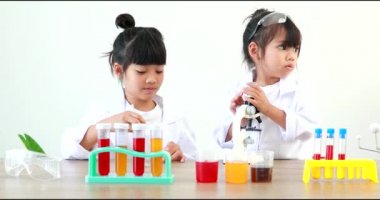 Küçük tatlı Asyalı öğrenci araştırma yapmayı ve kimyasal deney yapmayı öğrenirken evdeki test tüpünde sıvıyı analiz edip karıştırıyor..