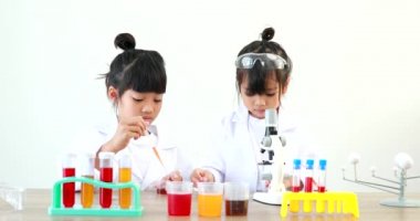 Küçük tatlı Asyalı öğrenci araştırma yapmayı ve kimyasal deney yapmayı öğrenirken evdeki test tüpünde sıvıyı analiz edip karıştırıyor..