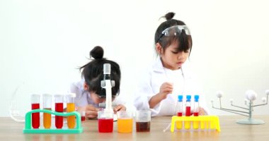 Küçük tatlı Asyalı öğrenci araştırma yapmayı ve kimyasal deney yapmayı öğrenirken evdeki test tüpünde sıvıyı analiz edip karıştırıyor..