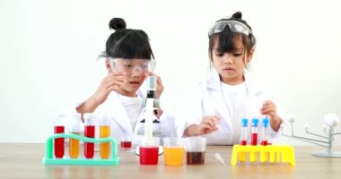 Küçük tatlı Asyalı öğrenci araştırma yapmayı ve kimyasal deney yapmayı öğrenirken evdeki test tüpünde sıvıyı analiz edip karıştırıyor..