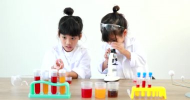 Küçük tatlı Asyalı öğrenci araştırma yapmayı ve kimyasal deney yapmayı öğrenirken evdeki test tüpünde sıvıyı analiz edip karıştırıyor..