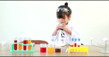 Küçük tatlı Asyalı öğrenci araştırma yapmayı ve kimyasal deney yapmayı öğrenirken evdeki test tüpünde sıvıyı analiz edip karıştırıyor..