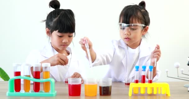 小さな女の子アジアの可愛いです少し学生子供学習研究と行う化学実験しながら作ると混合液でテストチューブに自宅でテーブルの上 — ストック動画