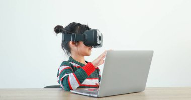 Evde gözlüklü VR giyen küçük kız sanal Global Internet bağlantısı metaevreninde oturuyor. Geleceğin beyaz elbiseli çocukları maç için VR kulaklık takıyor. kavramsal gelişmiş teknoloji. 