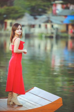 Beautiful Asian Chinese Woman Wearing Cheongsam Traditional Red Dress on Chinese New Year travel on vacation Posting on a boat in the river. 