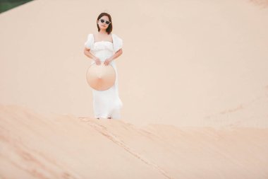 Beyaz elbiseli bir kadının portreleri aydınlık bir yaz gününde Mui Ne çölündeki Vietnam bayramı konseptinde yürüyor..