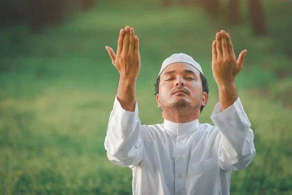 Religious muslim man  traditional kandura praying  outdoor at quiet nature  environment sun beams.