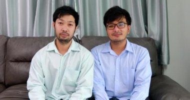 Happy homosexual male couple spending time together on sofas inside their homes.Happy together concept.