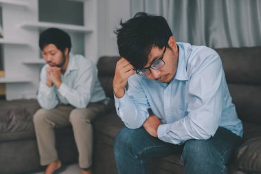 Homosexual male express sad or bad emotion from arguement or controversial problem. on sofas inside their homes, LGBTQ concept.