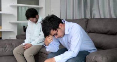 Happy homosexual male couple spending time together on sofas inside their homes.Happy together concept.