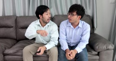 Happy homosexual male couple spending time together on sofas inside their homes.Happy together concept.