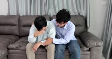 Happy homosexual male couple spending time together on sofas inside their homes.Happy together concept.