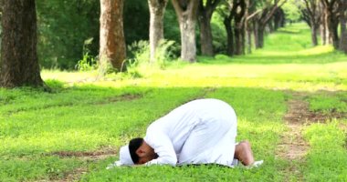 Religious muslim man traditional kandura praying outdoor at quiet nature  environment sun beams.