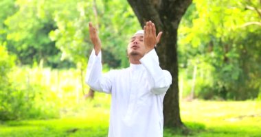 Religious muslim man traditional kandura praying outdoor at quiet nature  environment sun beams.