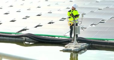 Portrait of professional man engineer working checking the panels at solar energy on buoy floating. Power plant with water, renewable energy source. Eco technology for electric power in industry.