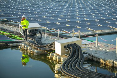 Portrait of professional man engineer working checking the panels at solar energy on buoy floating. Power plant with water, renewable energy source. Eco technology for electric power in industry.
