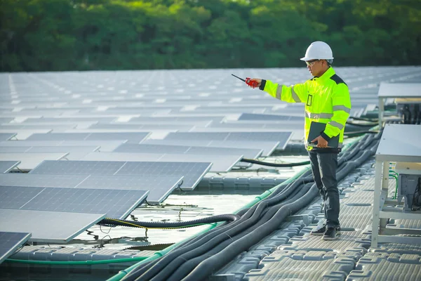 Portrait of professional man engineer working checking the panels at solar energy on buoy floating. Power plant with water, renewable energy source. Eco technology for electric power in industry.