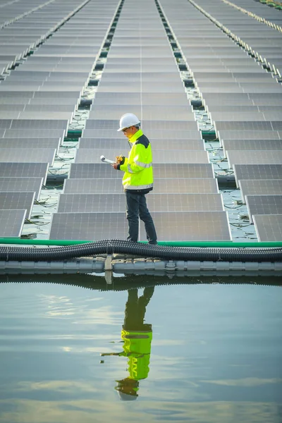 Portrait of professional man engineer working checking the panels at solar energy on buoy floating. Power plant with water, renewable energy source. Eco technology for electric power in industry.