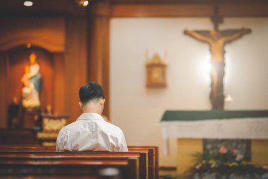 Kilisede oturan beyaz gömlek giyen Asyalı sakallı bir Hıristiyan.