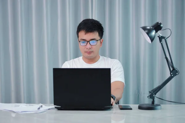 technology, remote job and lifestyle concept - happy asian man  man in glasses with laptop computer working at home office or online shopping, home work, freelance, online learning, studying.
