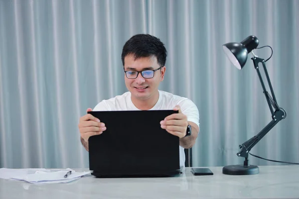 technology, remote job and lifestyle concept - happy asian man  man in glasses with laptop computer working at home office or online shopping, home work, freelance, online learning, studying.