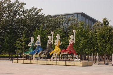 koşucular Olimpiyat Meşalesi koşusu sırasında heykelleri